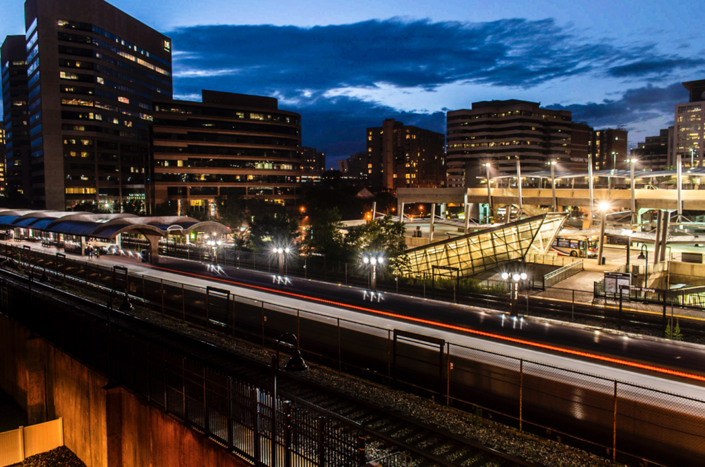 Street photography - An evening light trail of the metro passing in front of the skyline of Silver Spring, Maryland