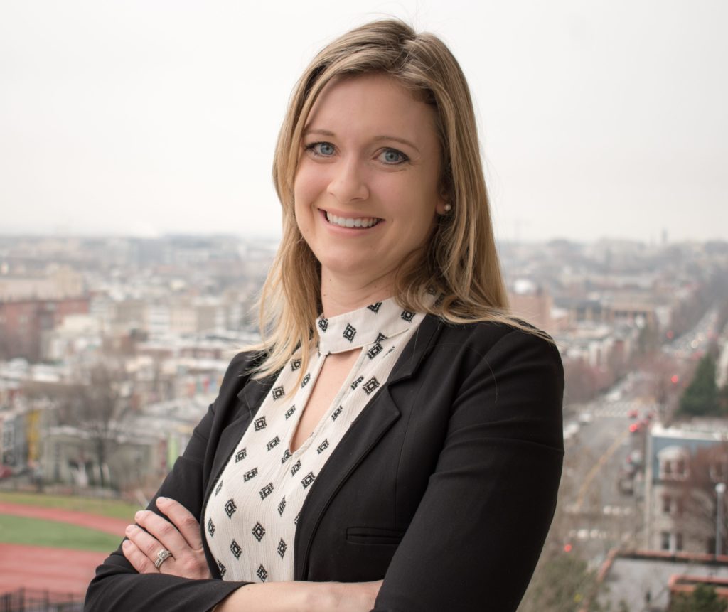 a beautiful blonde woman poses for a headshot with the Washington, DC skyline