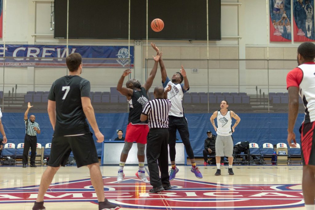 An action shot of two teams battling for the basketball at tip-off