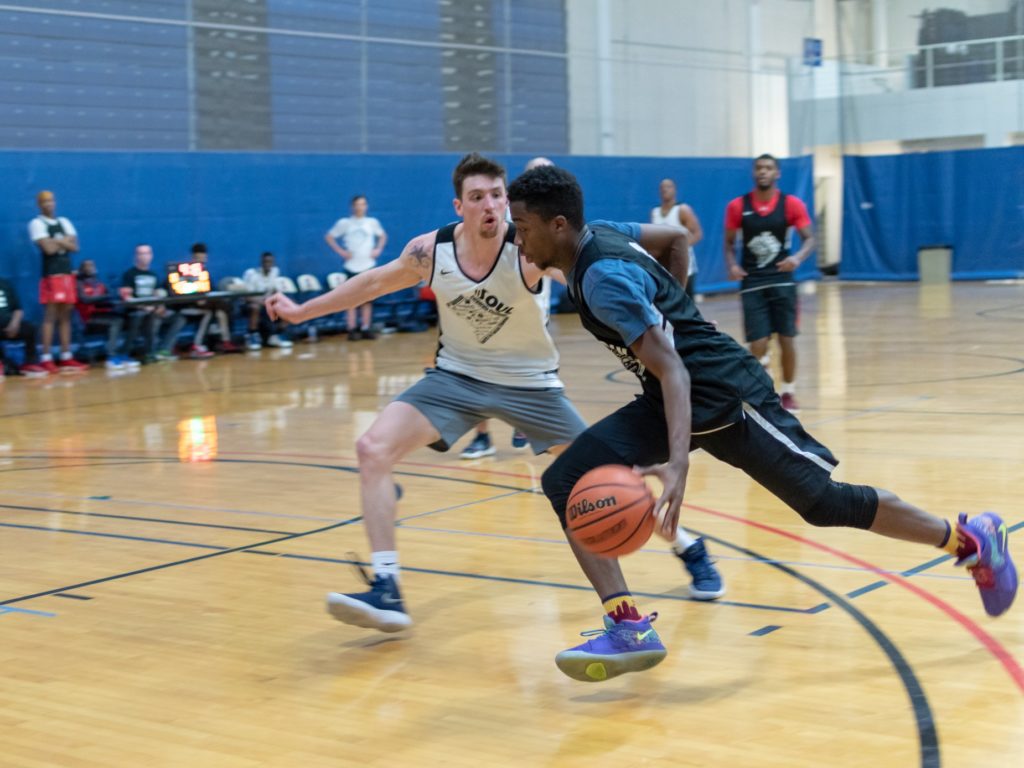 A photograph of a basketball player dribbling around his opponent