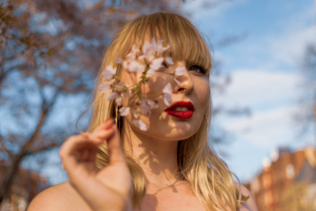 A blonde model poses with a cherry blossom in Washington, DC