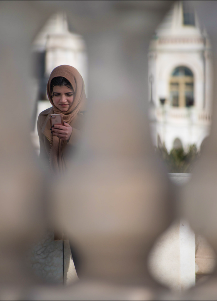 A young Muslim girl looks at her phone in front of the United States Capitol in Washington, DC