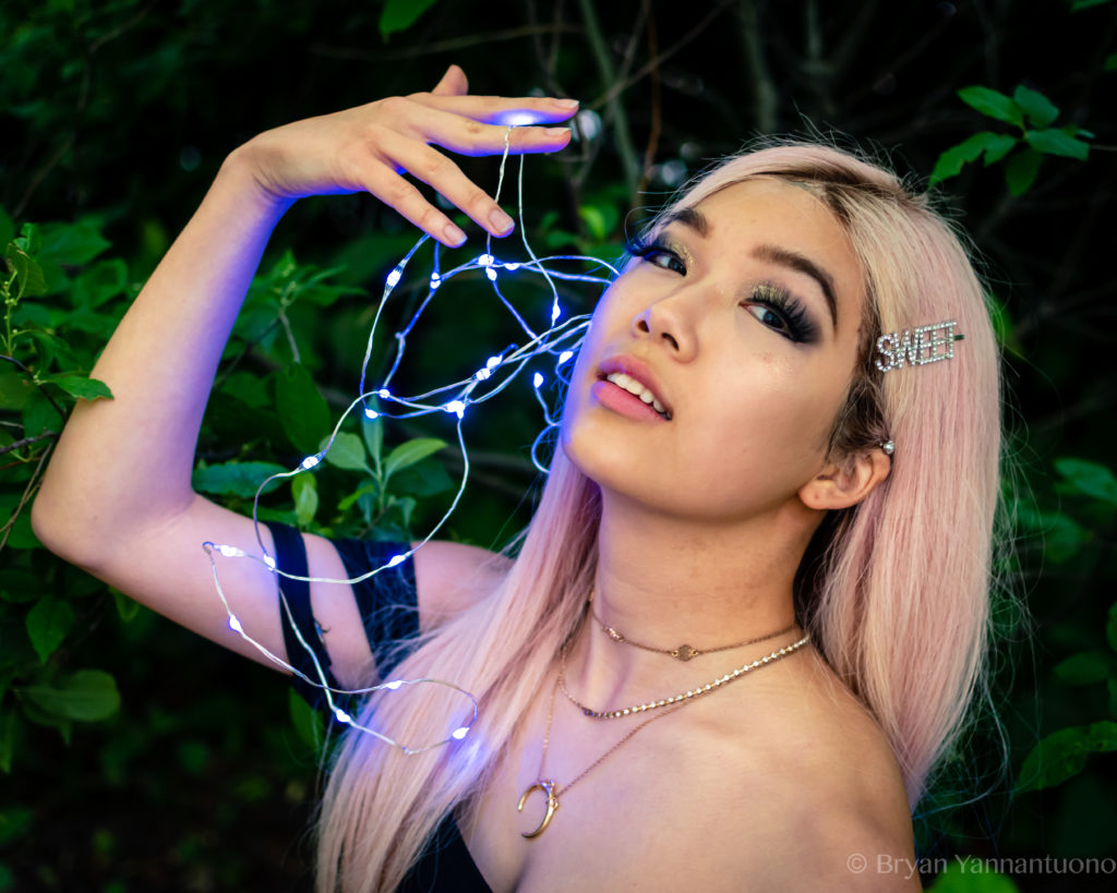 Portrait photography of a young female model poses with blue fairy lights