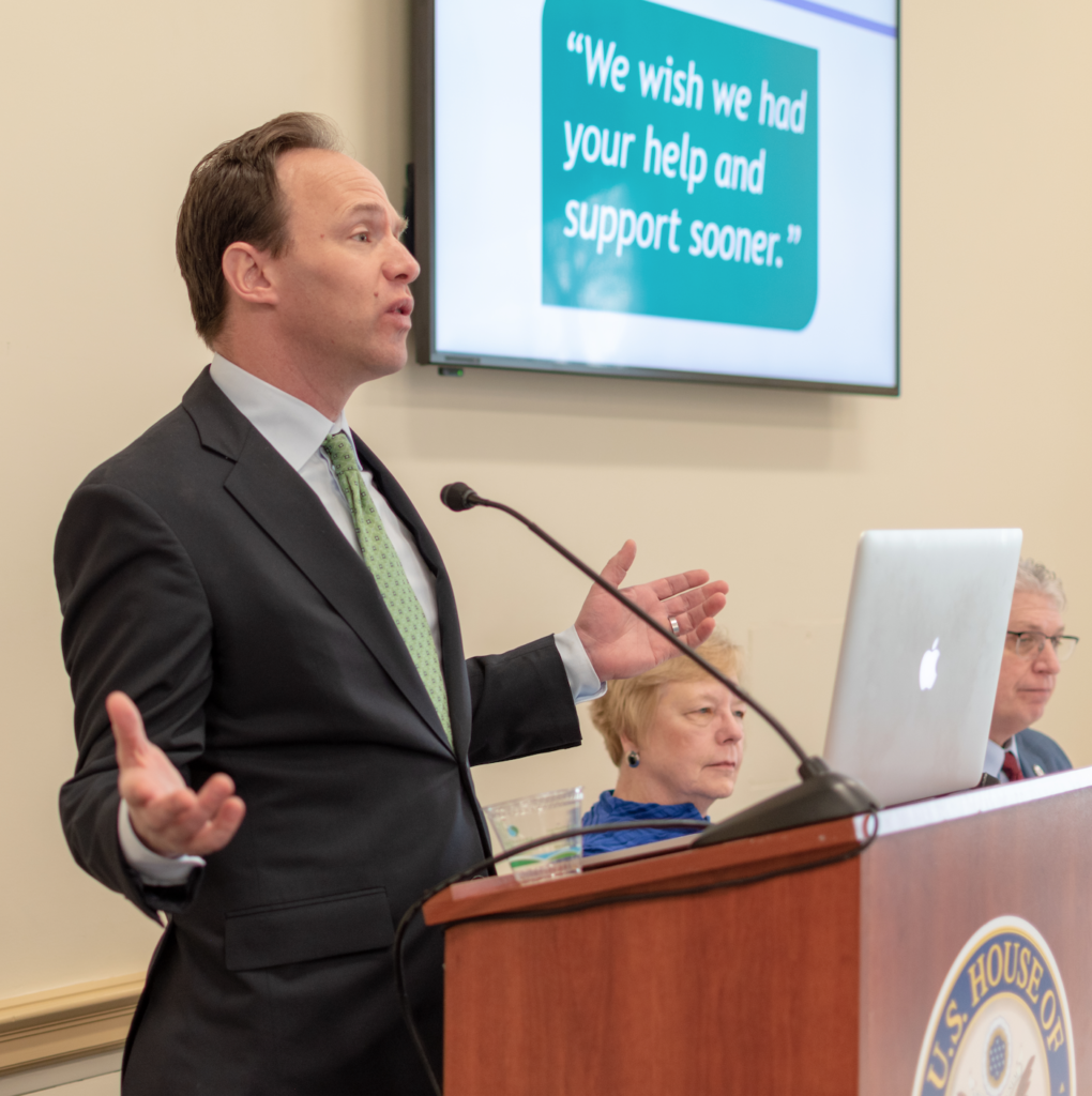 A man speaks at a podium and delivers a presentation at a capitol hill briefing